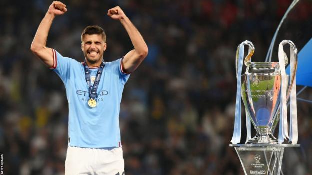 Manchester City'nin orta saha oyuncusu Rodri, Şampiyonlar Ligi kupasının önünde kutlama yapıyor