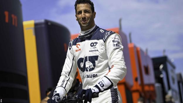 Alpha Tauri pilotu Daniel Ricciardo, Macaristan Grand Prix'sinde padokta scooter sürerken gülümsüyor